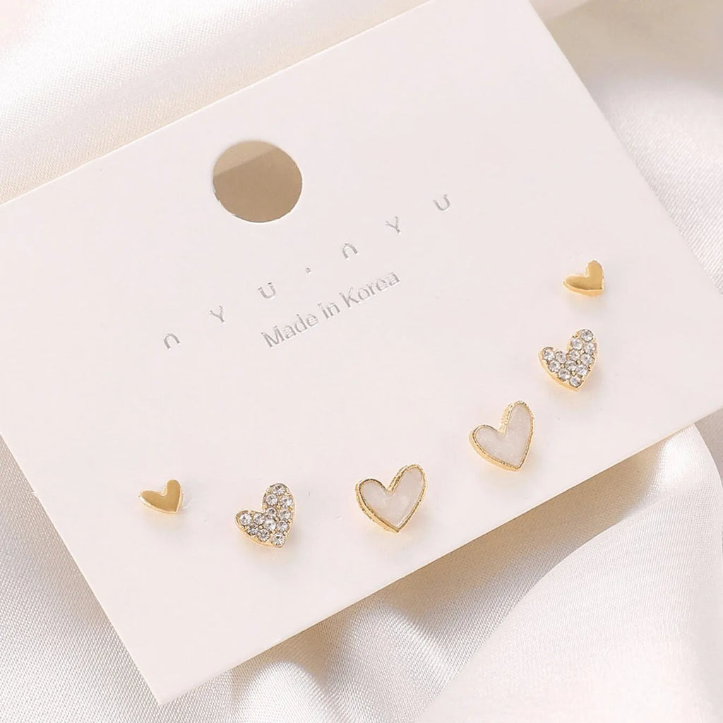 Three pairs of women's heart-shaped alloy earrings in gold, black, white and pink electroplated finishes
