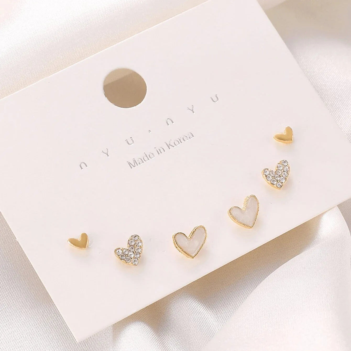 Three pairs of women's heart-shaped alloy earrings in gold, black, white and pink electroplated finishes