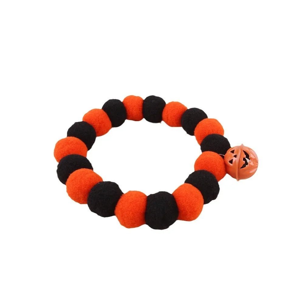 Orange Halloween cat collar with a pumpkin graphic and metal jingle bell on a black background.