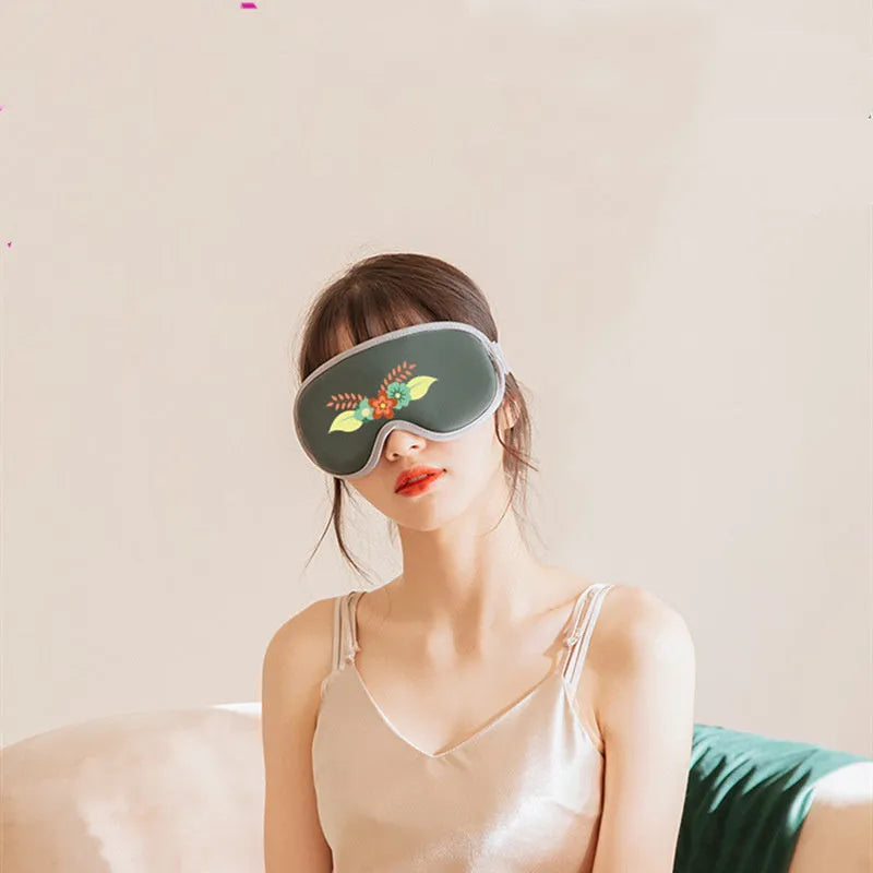 Green portable eye spa massage goggles with USB cable on a table.