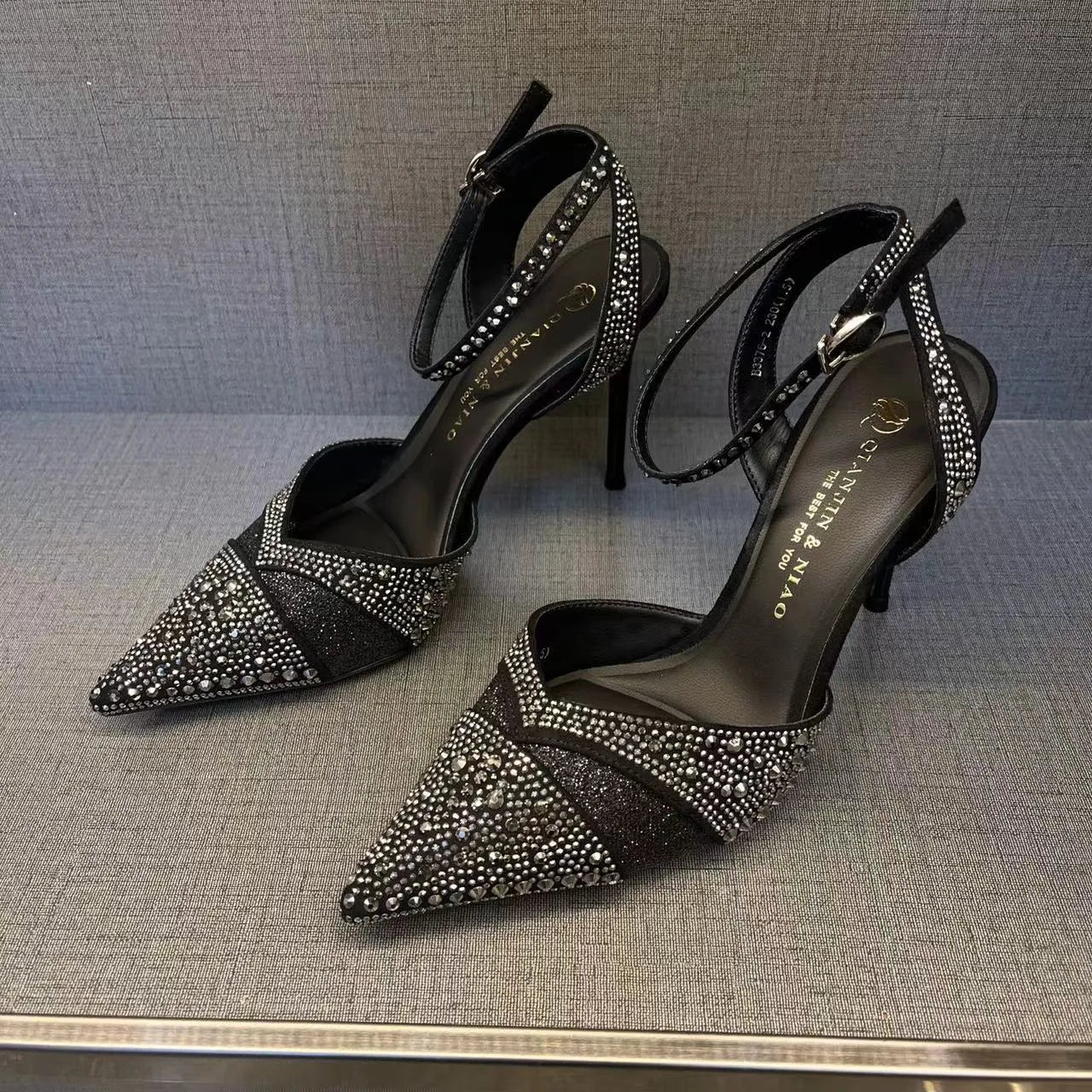 Women's black high heel shoe with stiletto heel, pointed toe, shallow cut, and red sole.