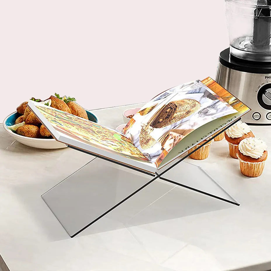 Clear acrylic X-shaped book display rack holding a book on a desktop