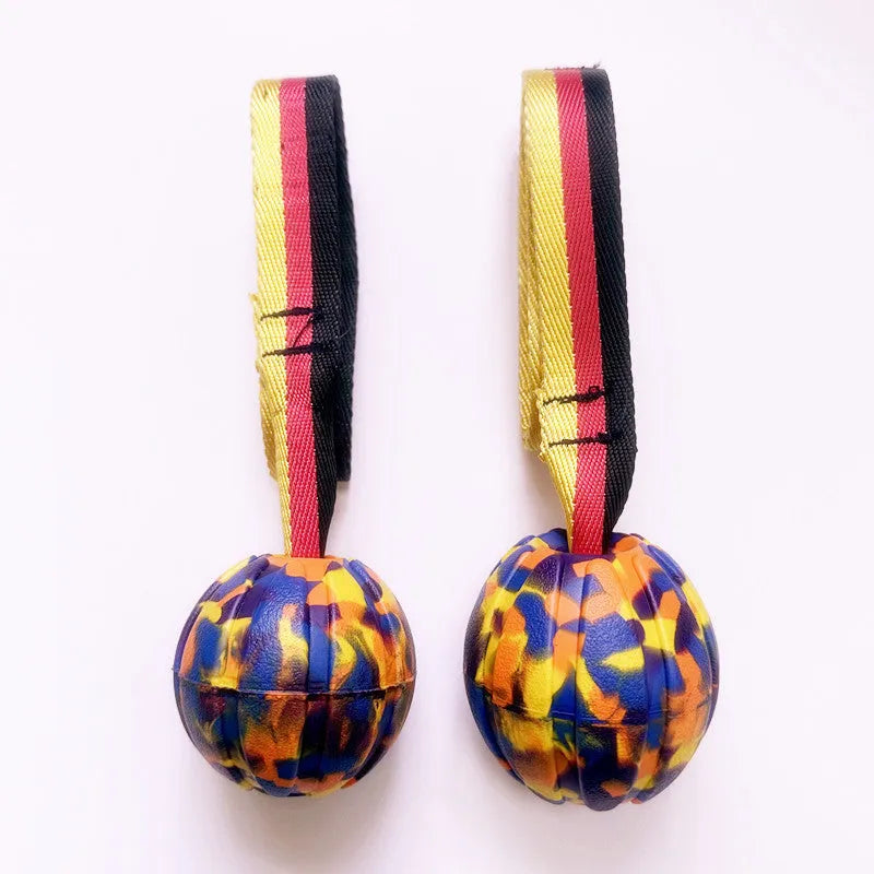 Yellow EVA floating dog ball with string attached, next to a camouflage coloured version on a blue background.