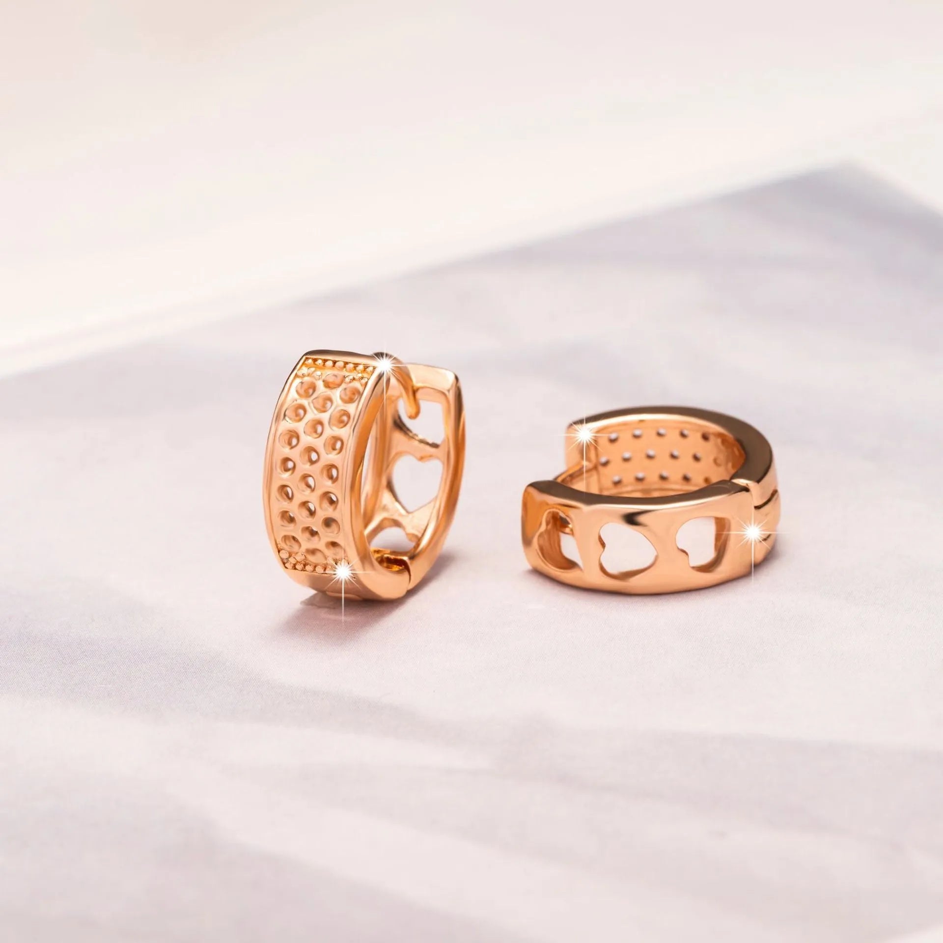 Rose gold electroplated earrings with three hollowed heart designs in circular shape