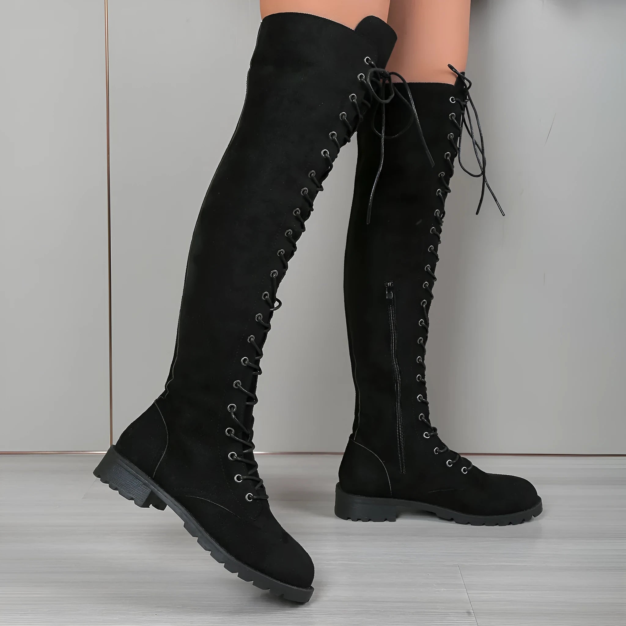 Women's black lace-up over-the-knee boots with a flat rubber sole and visible stitching detail.