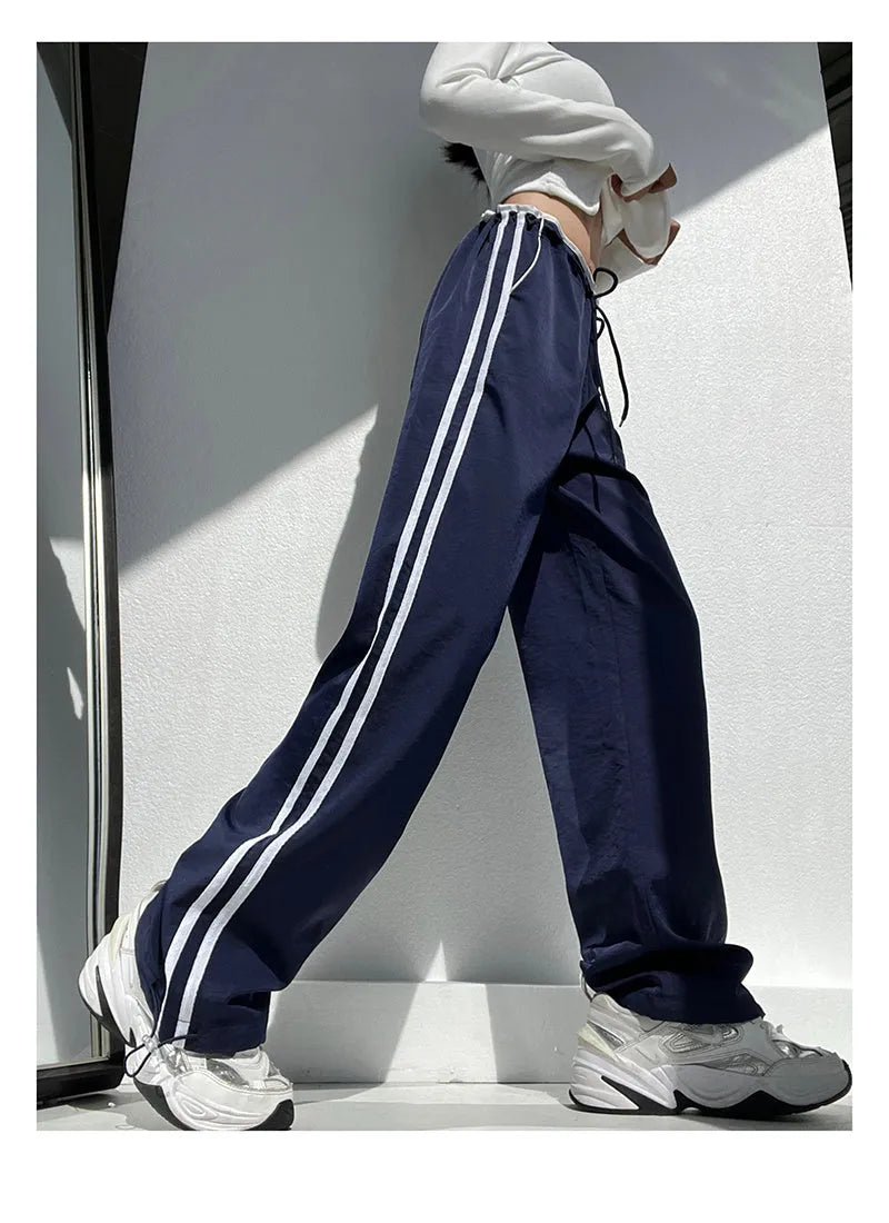 Navy blue loose straight-leg trousers with ribbon-adjustable waist and parallel bars design detail.