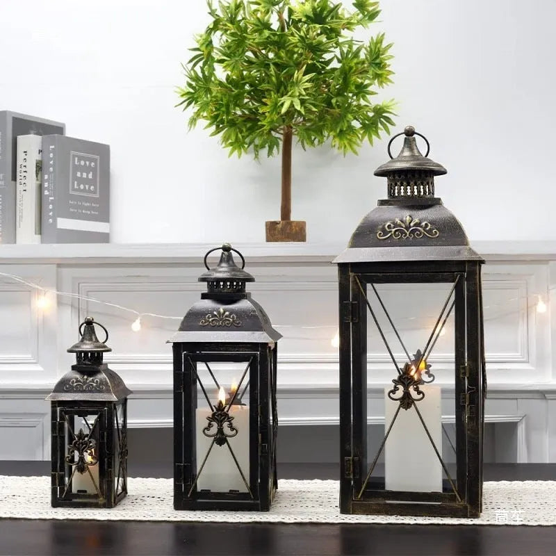 Black wrought iron floor lantern with tempered glass panels, standing on a patio.