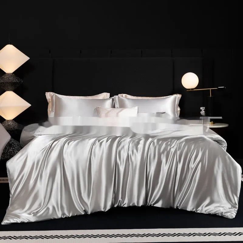 Silk four-piece bed sheet set in a solid colour on a bed, showing duvet cover and pillowcases.