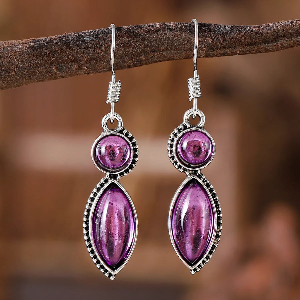 A pair of vintage geometric drop earrings with black and purple stones in a bohemian style.
