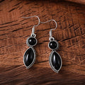 A pair of vintage geometric drop earrings with black and purple stones in a bohemian style.
