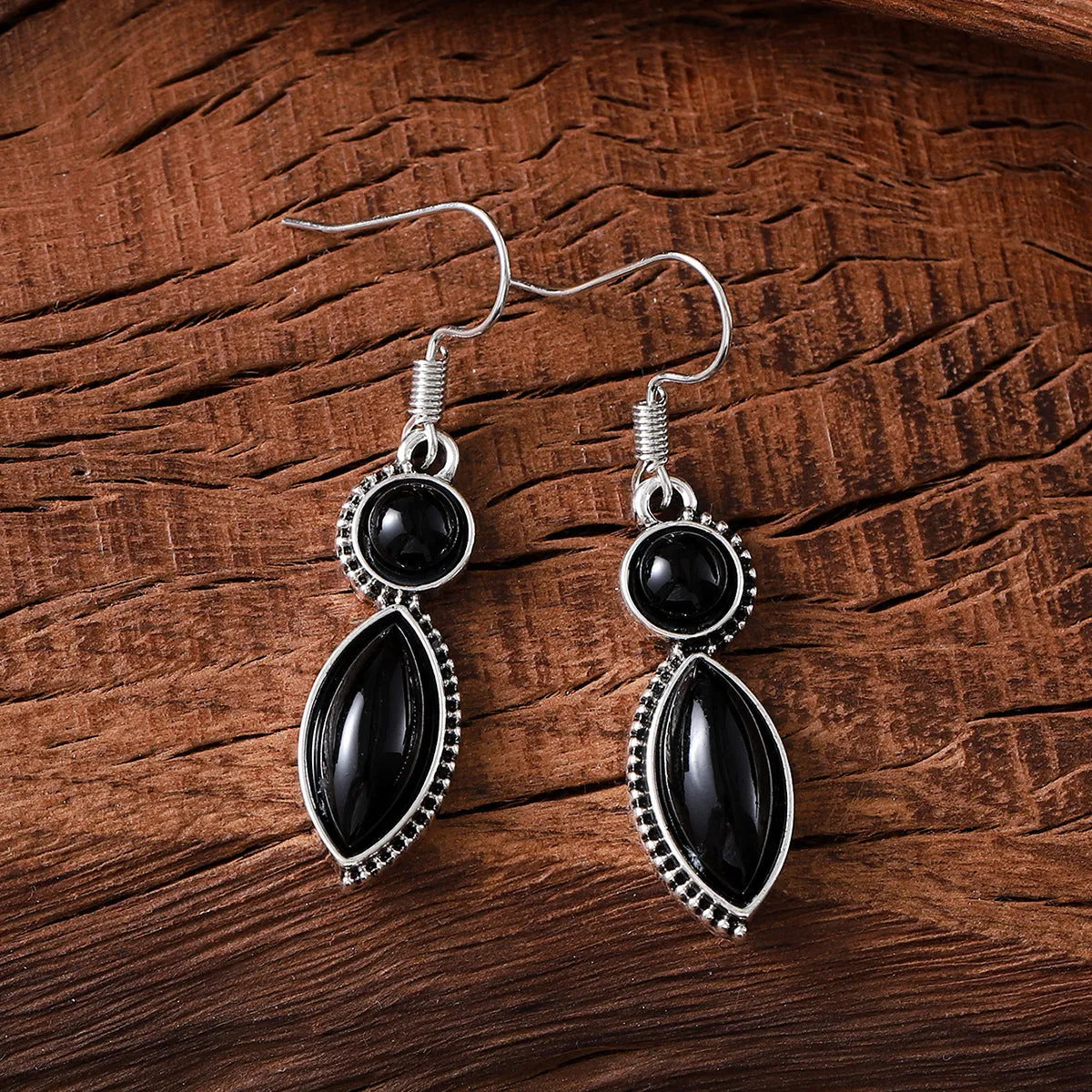 A pair of vintage geometric drop earrings with black and purple stones in a bohemian style.