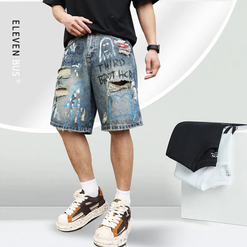 Blue mens denim shorts with ripped knees and graffiti design, straight leg fit.