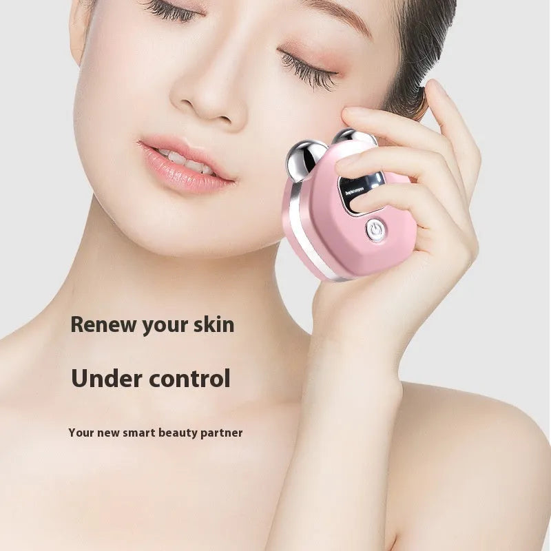 Portable white handheld facial massager with dual rollers and hot compress function on a pink background