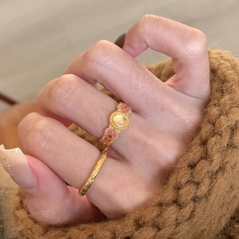 Open-mouth geometric women's ring with gold plating and pink crystal enamel detail on a white background.