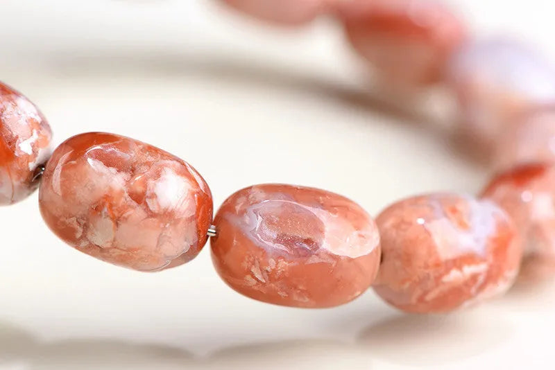 Natural cherry agate barrel bead bracelet with Ruyi design elements on wrist