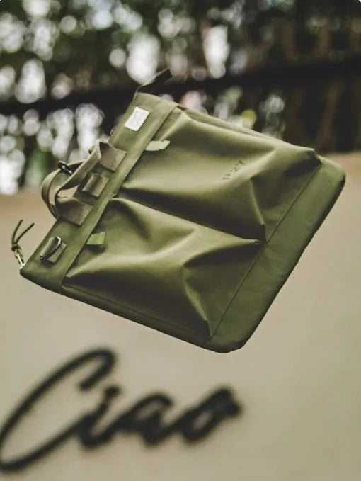 Canvas crossbody messenger bag in military green with shoulder strap and hard handle showing laptop compartment