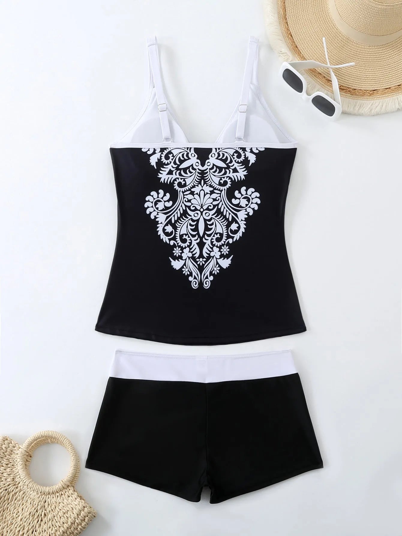 A plus size woman wearing a black two-piece printed swimsuit at the beach.