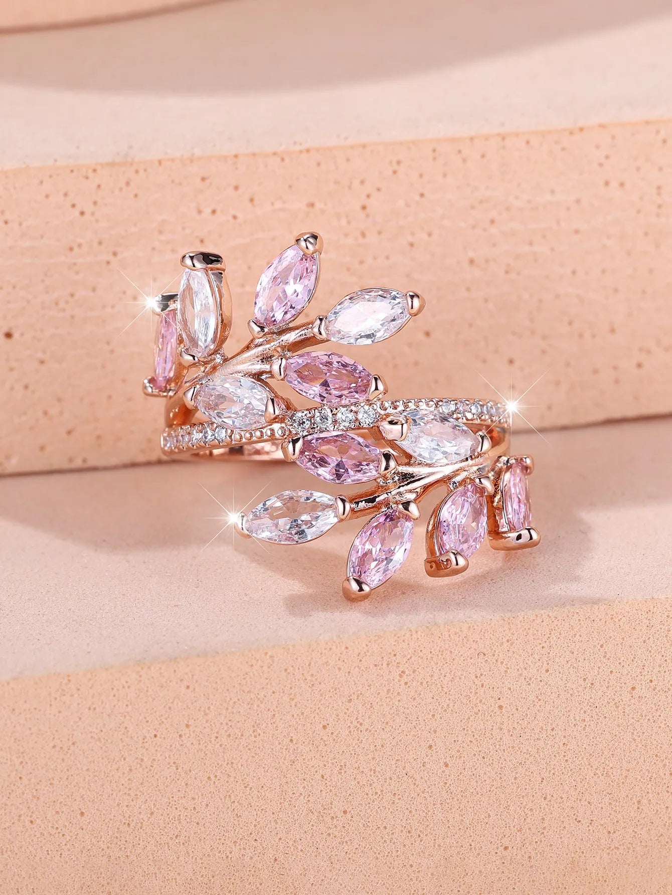 Adjustable opening copper leaf fashion ring with sparkling zirconia stones in a rose gold finish.