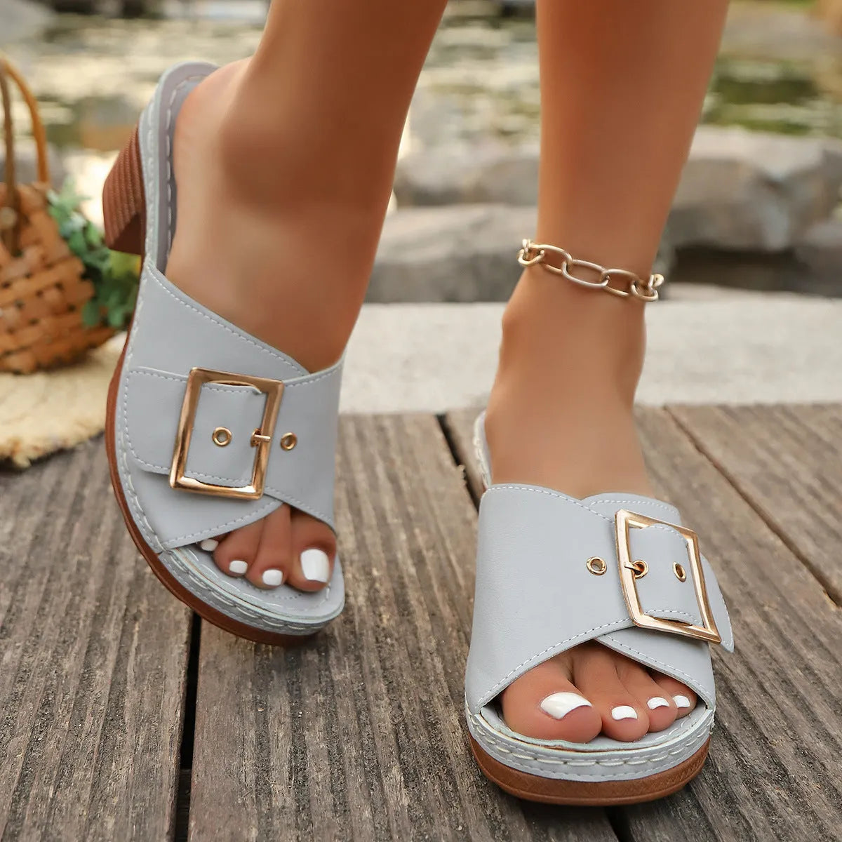 Women's black chunky heel slippers with a round toe and large metal buckle on a rubber sole.