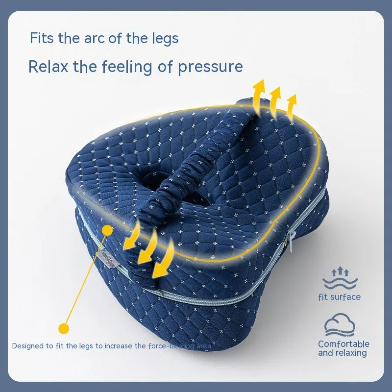 Heart-shaped dark blue memory foam leg pillow for adults on a bed.