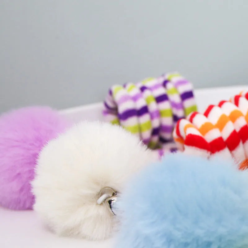 Colourful suction cup cat toy with spring wand and inflatable ball, hanging on a glass door