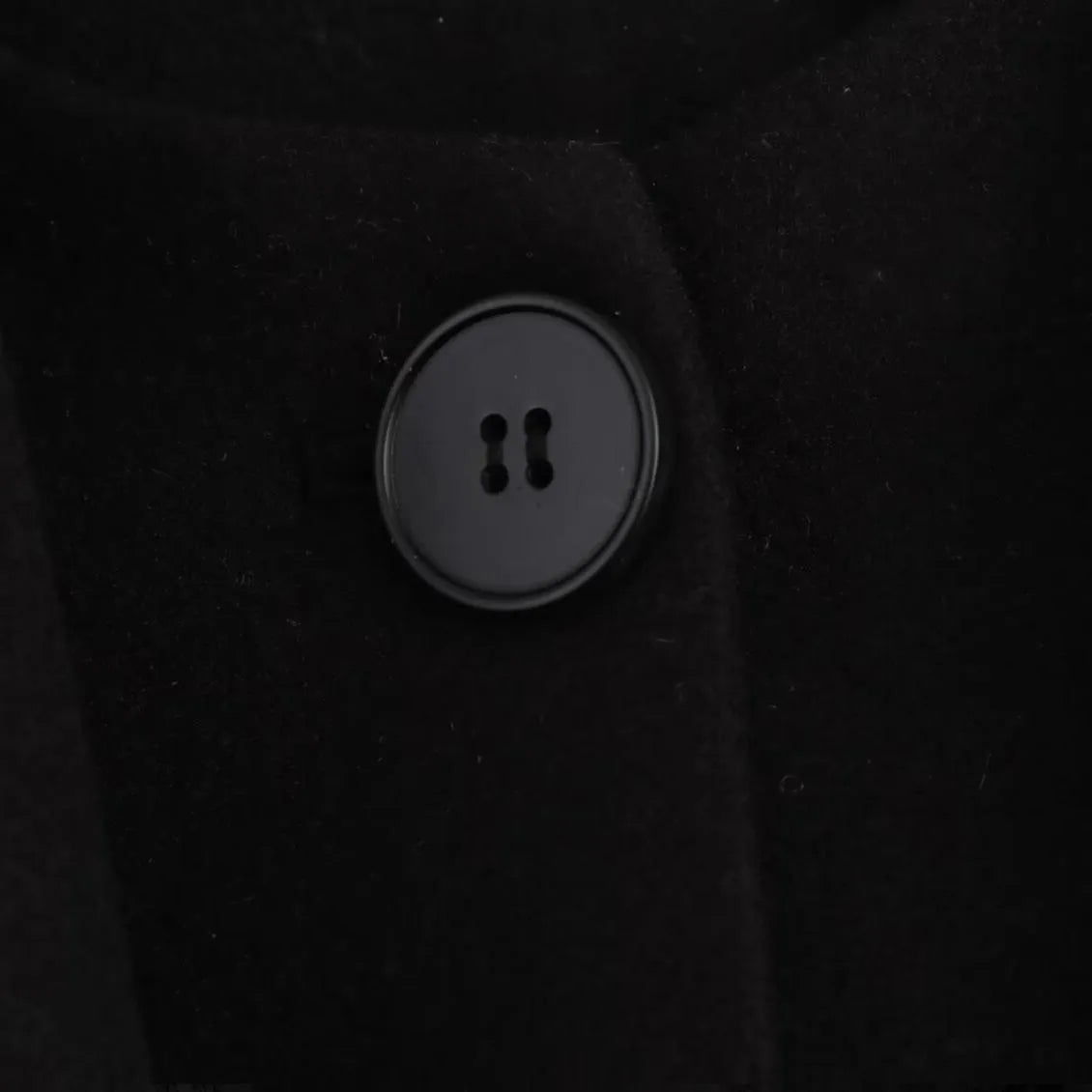 Women's long black coat with a detachable grey artificial fur collar, showing longline silhouette and side pockets.