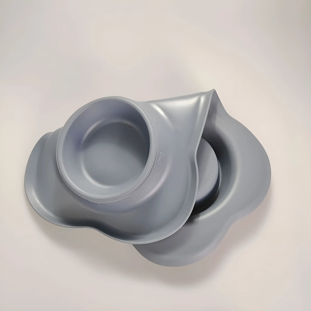 Large black silicone dog bowl sitting inside a stainless steel base, shown on a kitchen floor.