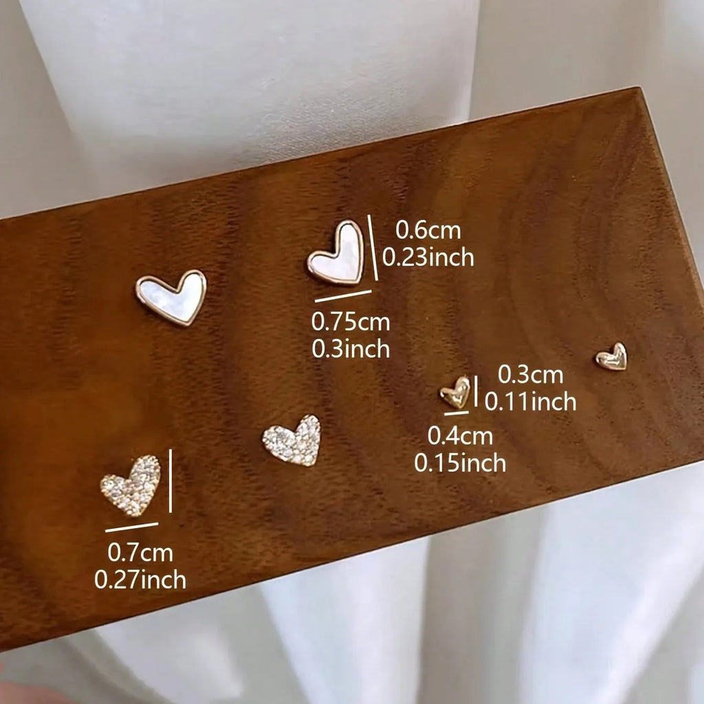Three pairs of women's heart-shaped alloy earrings in gold, black, white and pink electroplated finishes