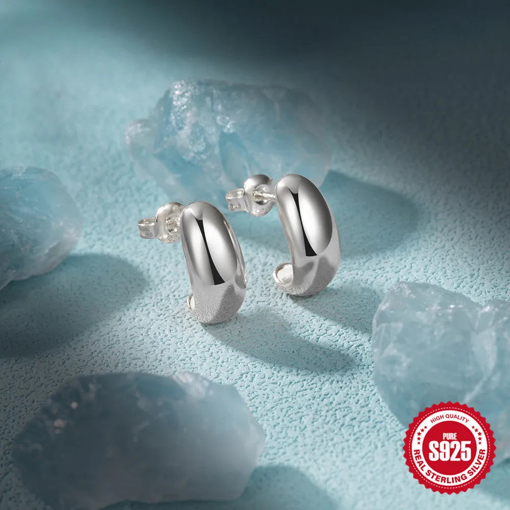 A pair of glossy C-shaped stud earrings in sterling silver, shown in gold and silver colour options.