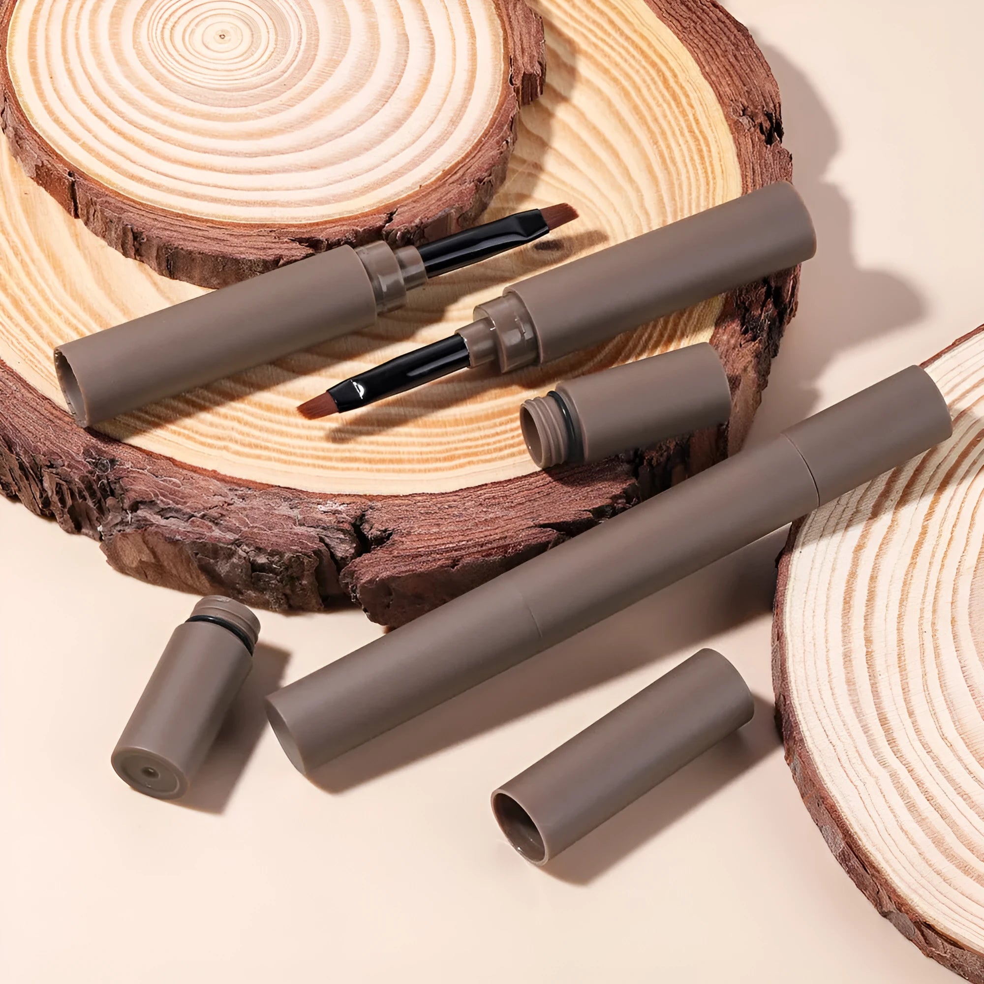 Double-headed eyebrow cream tube shown next to swatches of its five colours: reddish brown, brown, light brown, dark brown, and black.
