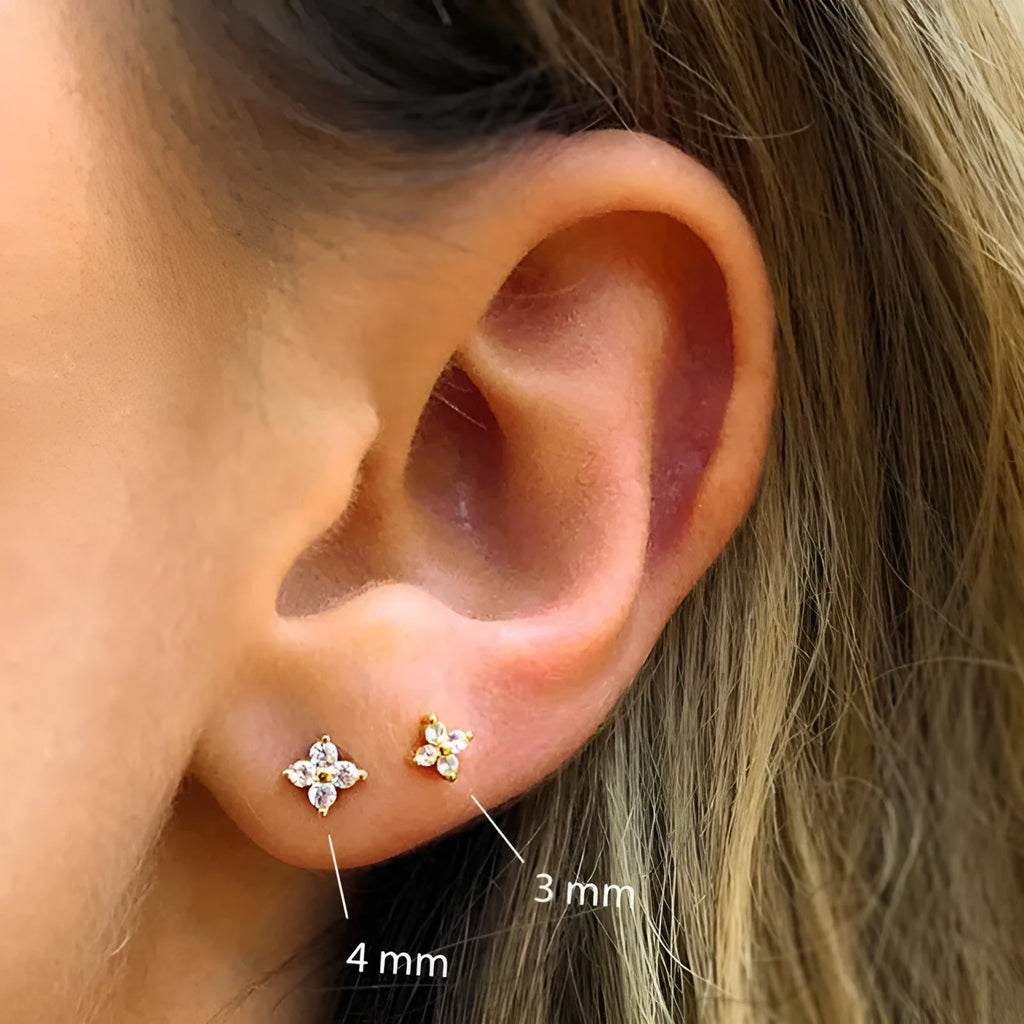 S925 sterling silver stud earrings with crystal flowers in gold and platinum finishes on a grey background.