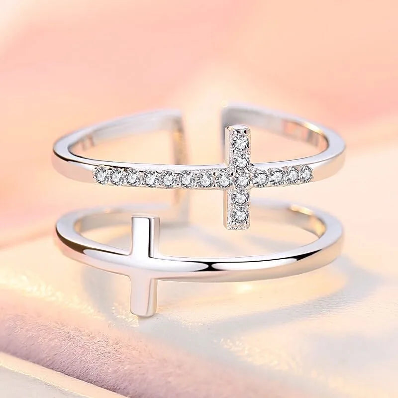 Adjustable open ring showing double cross design with zircon stones and sterling silver inlay on copper.