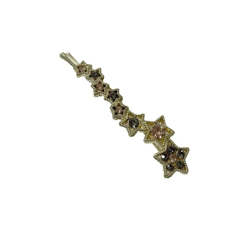 Gold-coloured alloy hair barrette with rhinestone star charm, shown clipped to hair.