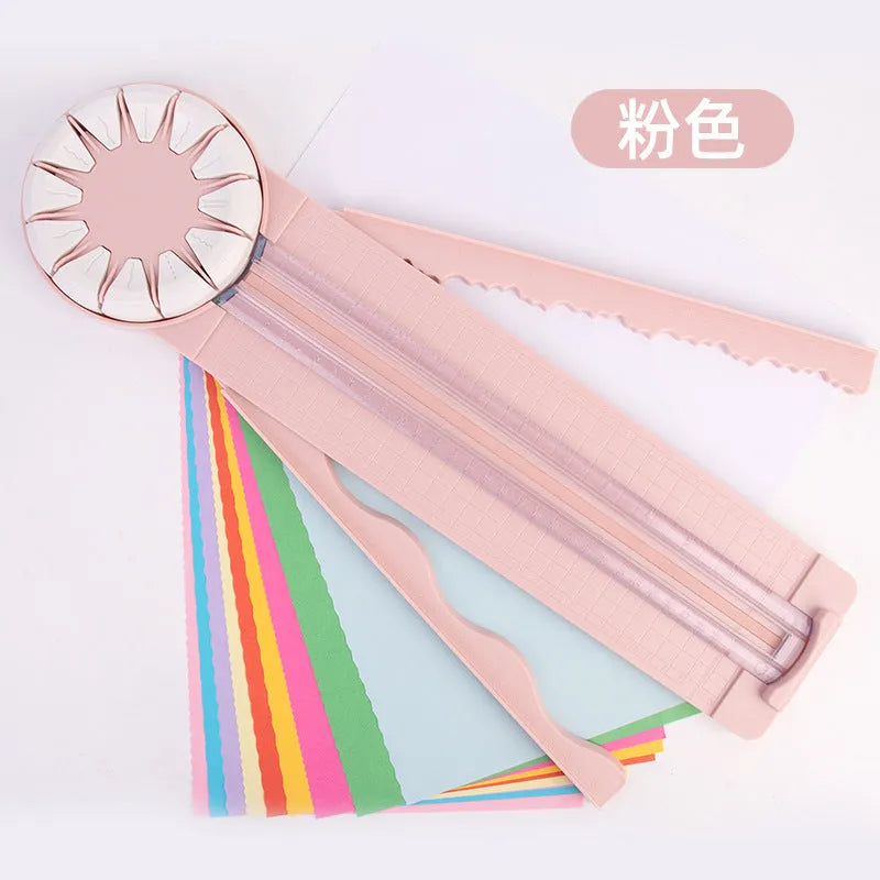 Pink plastic 12-in-1 paper cutting machine with dotted perforation wheel on craft table