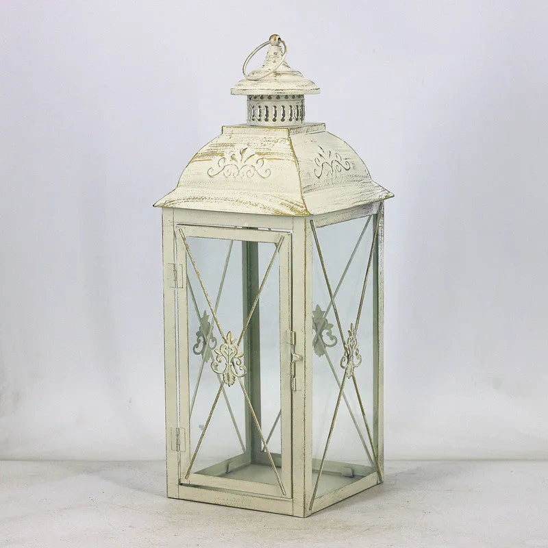 Black wrought iron floor lantern with tempered glass panels, standing on a patio.