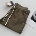 Man wearing loose straight-leg casual trousers in beige with a drawstring waistband.