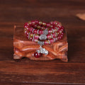 Handmade bracelet with watermelon crystal beads and a red Chinese knot on a white background.