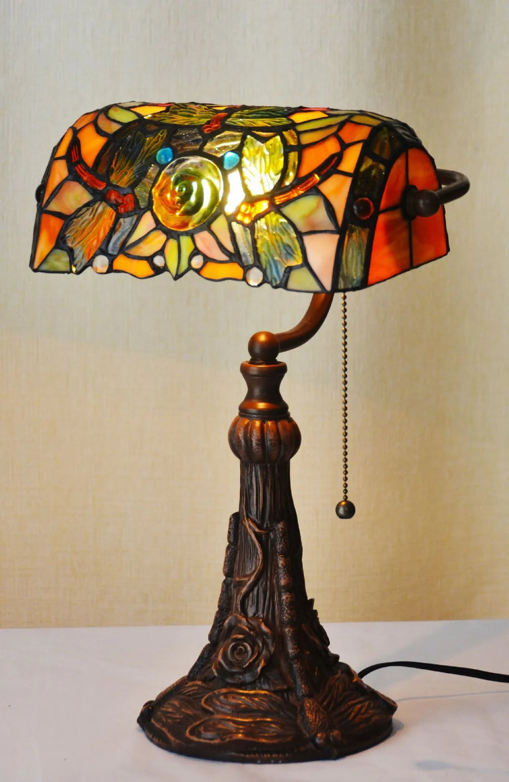 10-inch Tiffany style table lamp with coloured stained glass shade and resin base on a desk.