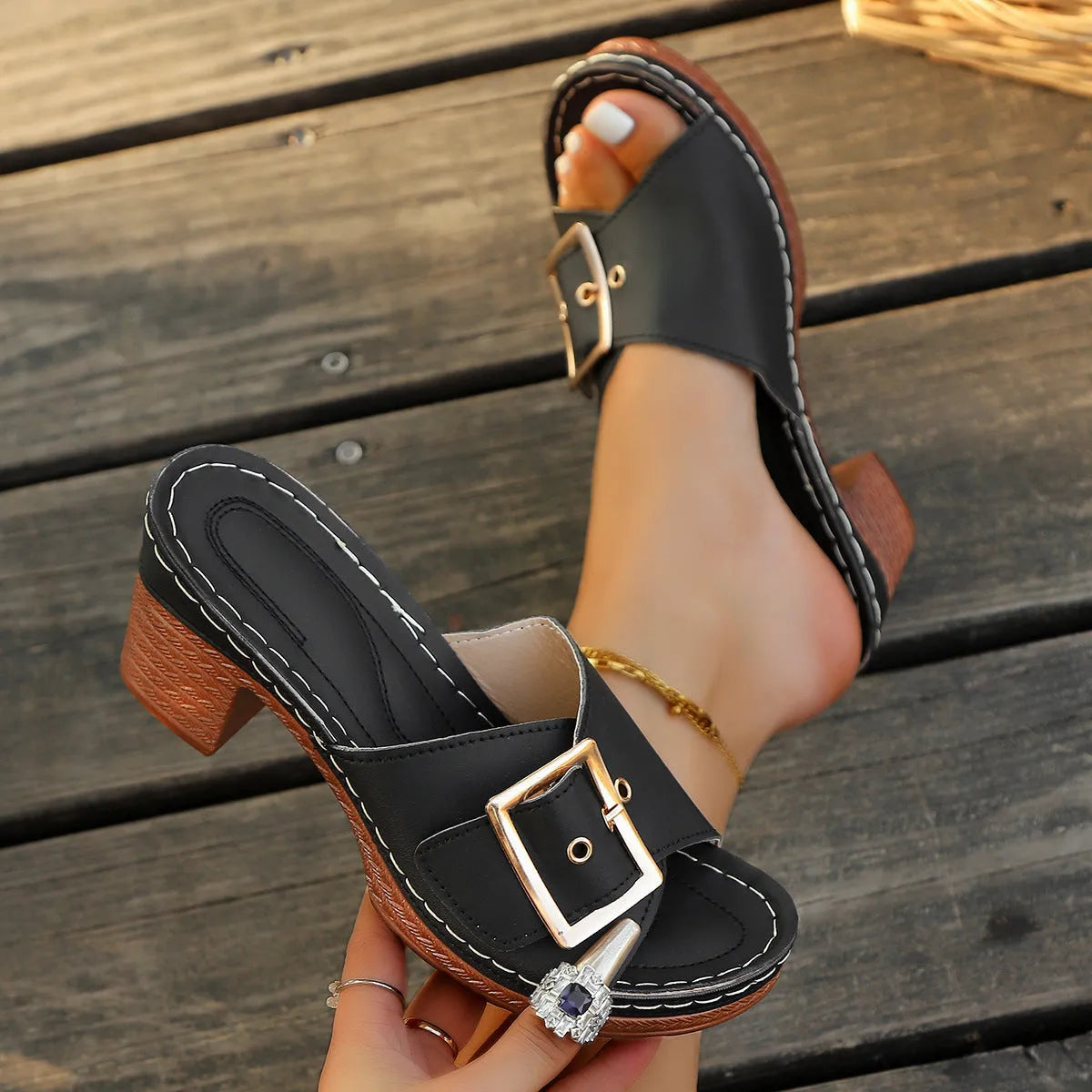 Women's black chunky heel slippers with a round toe and large metal buckle on a rubber sole.