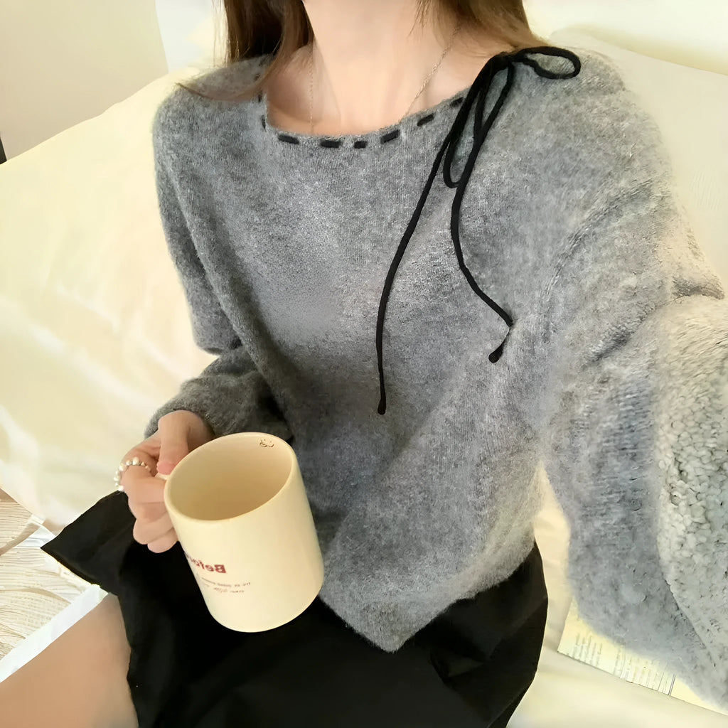 A grey loose-fitting women's knitwear pullover sweater on a hanger.