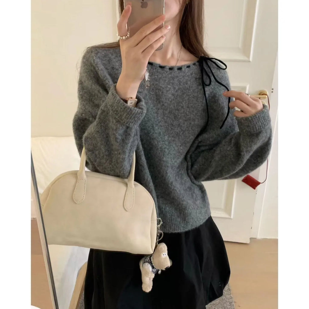 A grey loose-fitting women's knitwear pullover sweater on a hanger.
