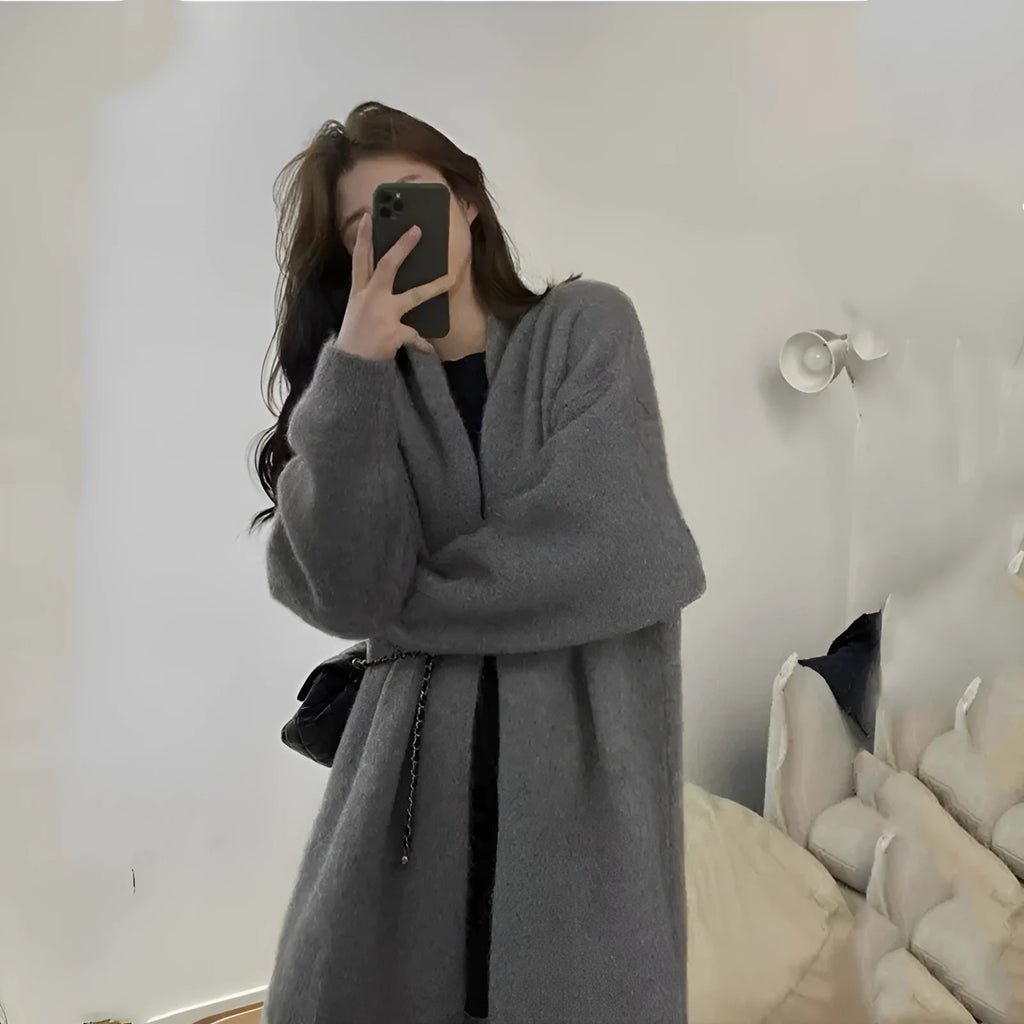 Loose large women's knitted cardigan in thick chenille fabric showing 3D pattern and regular sleeves.