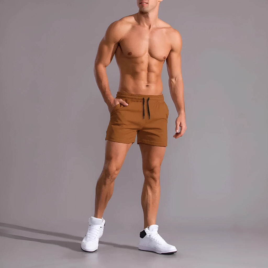 Men's black, khaki, and light brown elastic drawstring shorts laid flat, showing loose fit and adjustable waistband.