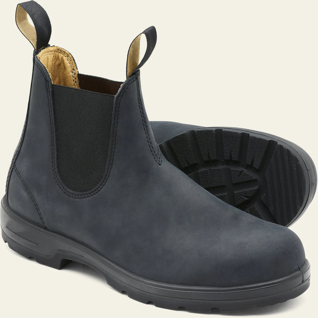 Vintage brown unisex Chelsea ankle boots with car suture stitching and a low heel on a wooden floor.