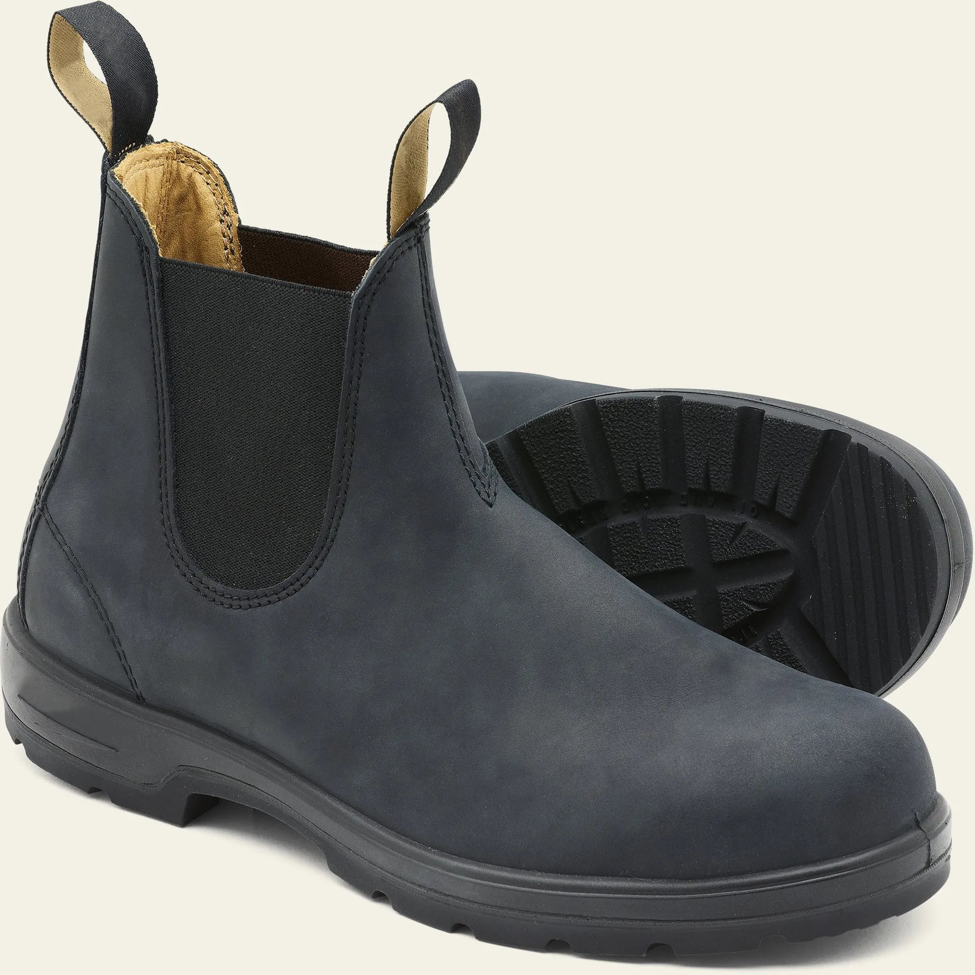 Vintage brown unisex Chelsea ankle boots with car suture stitching and a low heel on a wooden floor.