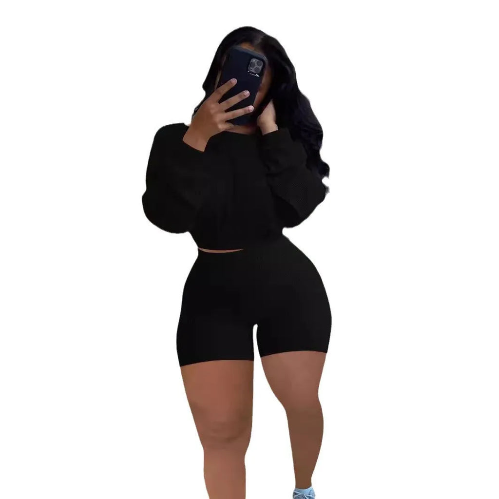 A woman wearing a solid colour off-the-shoulder long-sleeved top and matching shorts from a two-piece set.