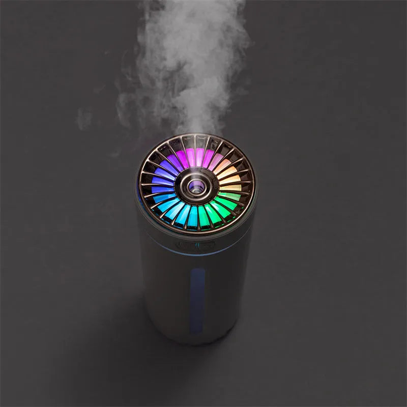Black portable USB rechargeable car humidifier with colourful lights on a desk next to a cup