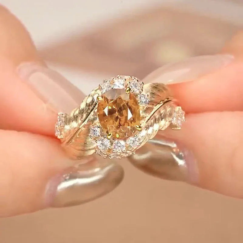 Gold-coloured copper ring with an embossed feather pattern and inlaid yellow zircon stones.