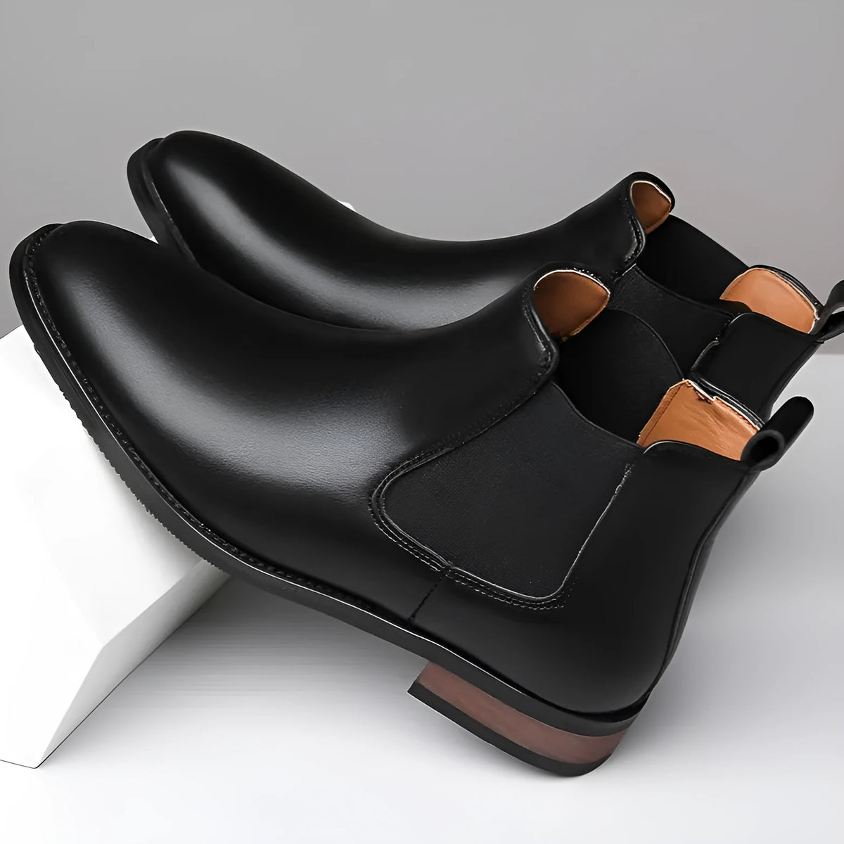 Men's black Chelsea high-top boots with round toe and rubber sole on a plain background.