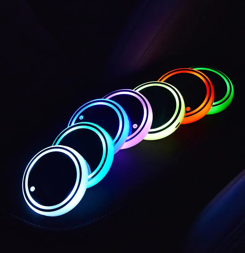 Colourful LED light-up coaster for car cup holder with USB cable on a car console.